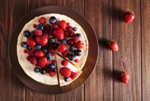 Top viev. Delicious Homemade creamy mascarpone New York Cheesecake with berries on dark wooden table. Close up.